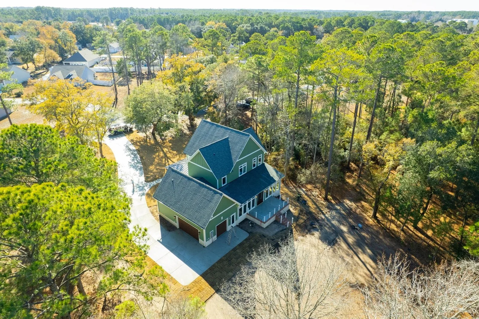 Aerial view of a home surrounded by pines near the water