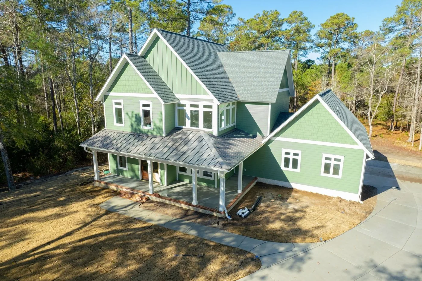 Newly completed two story home with green siding and a covered front porch