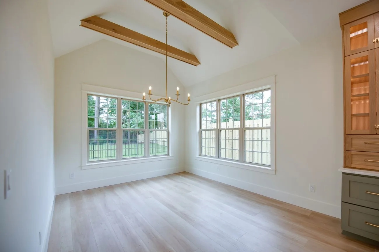 Vaulted living room with exposed beams and a built-in cabinet wall