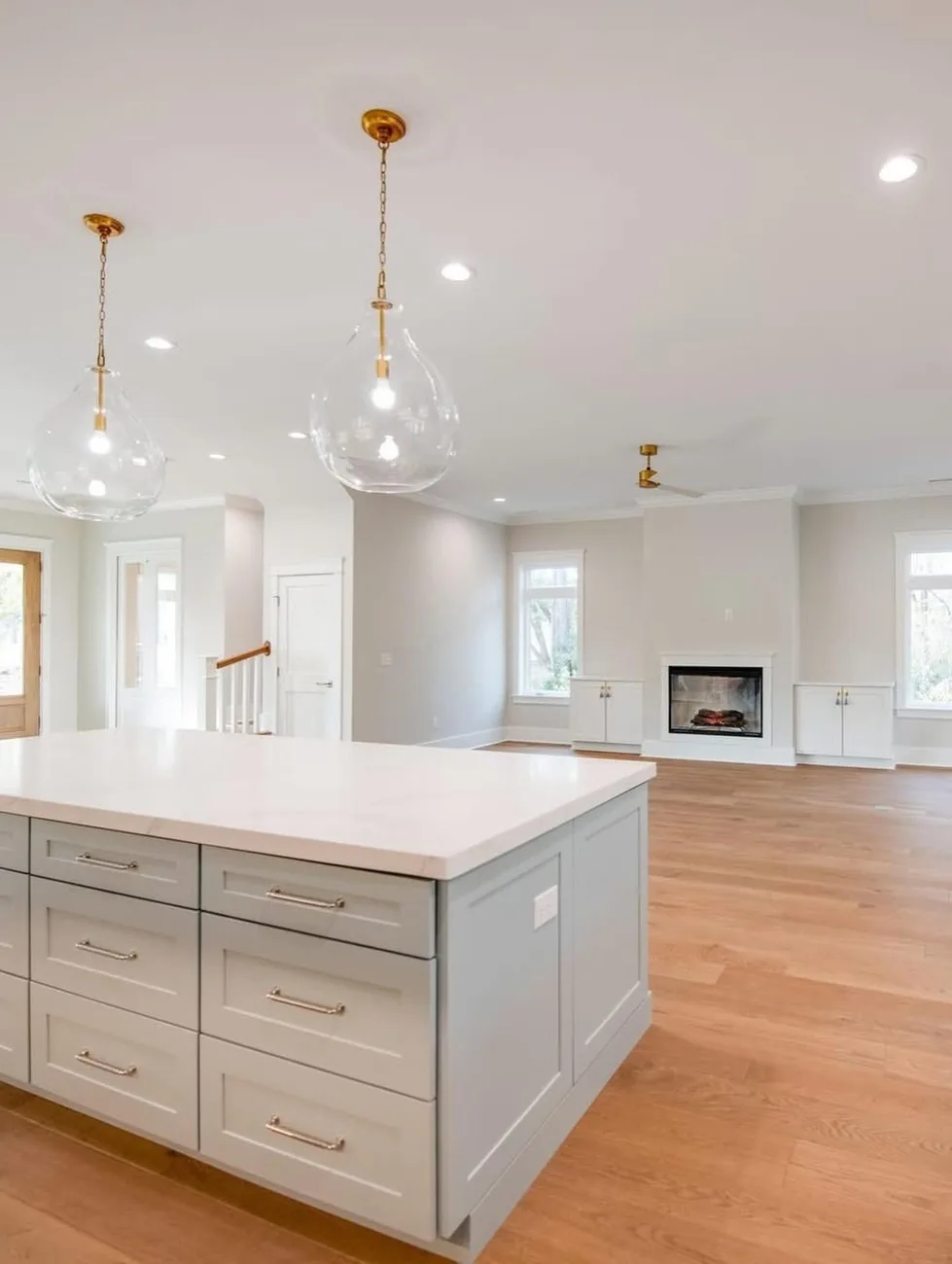 Open kitchen with a stone island, pendant lighting and a fireplace beyond