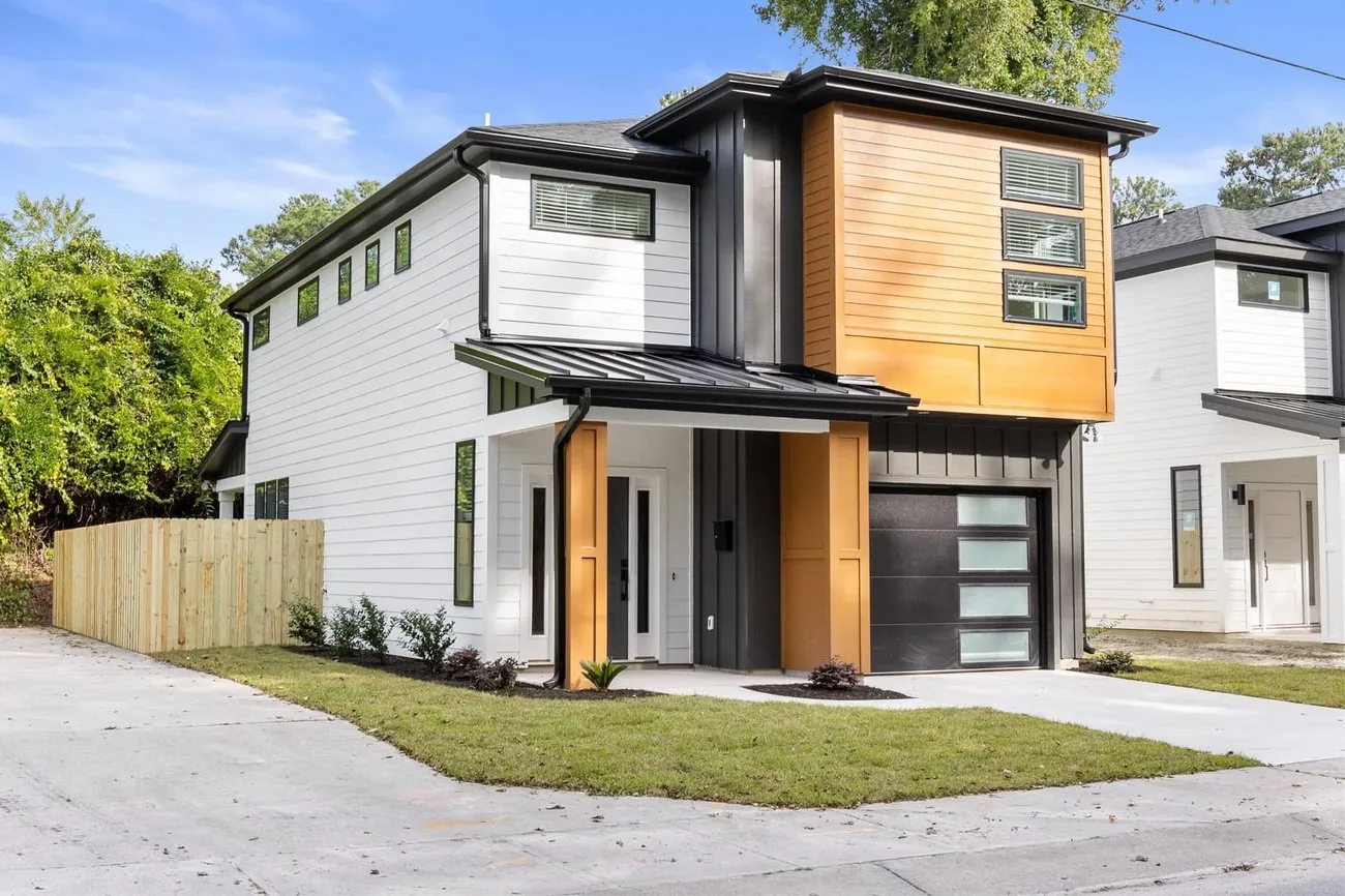 Modern coastal home with mixed wood and painted siding and a two car garage