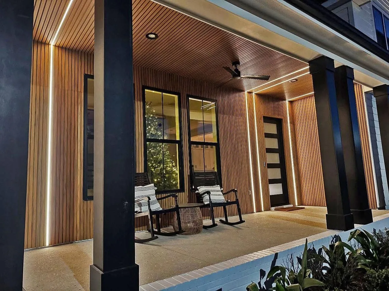 Covered porch with a wood slat ceiling and dark columns beside a pool